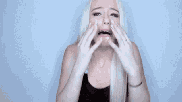 a woman with blonde hair is making a funny face with her hands .