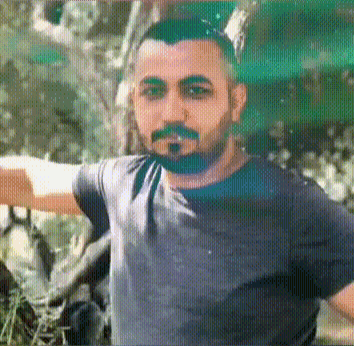 a man with a beard is standing with his arms outstretched in front of a tree .