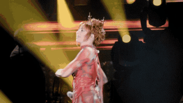 a woman in a red dress sings into a microphone on a stage