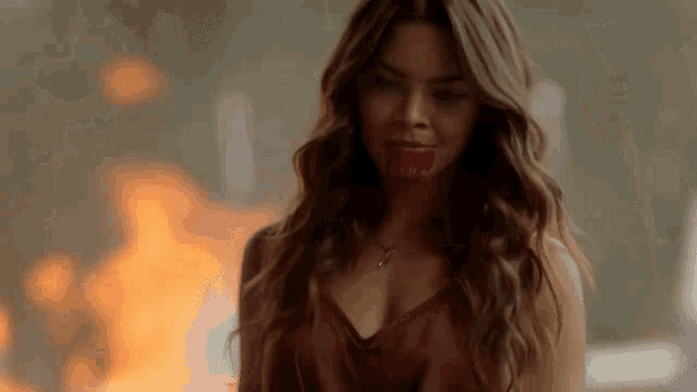 a woman with red lips is standing in front of a fire
