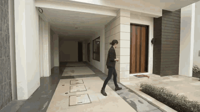 a woman walking in front of a house with the number 0 on the side