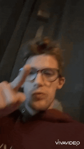 a man wearing glasses and a red hoodie is being filmed by vivavideo