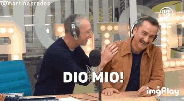 two men are laughing in front of a microphone and the words dio mio are displayed on the screen