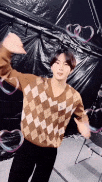 a young man in a plaid sweater is surrounded by soap bubbles in the shape of hearts