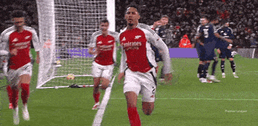 a soccer player is celebrating a goal on a soccer field with his team mates .