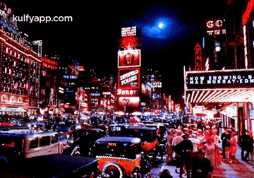 a busy city street at night with the words kulfyapp.com in the corner