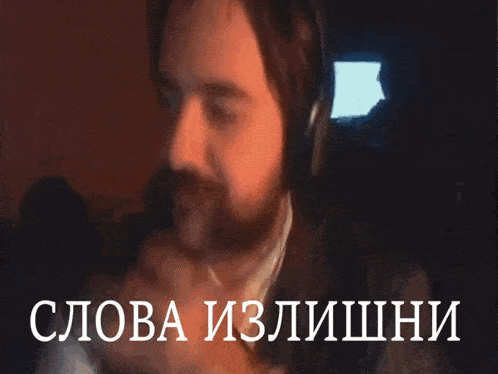 a man wearing headphones is singing into a microphone with the words слова излишни above him