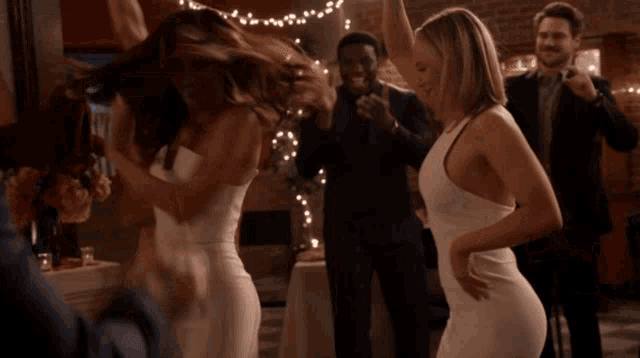 a group of people are dancing in a room with christmas lights