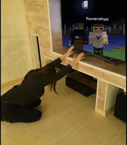 a woman is kneeling in front of a television with romanskyy written on the screen