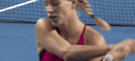 a woman in a pink tank top is holding a tennis racquet .