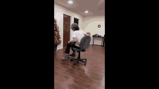 a person is sitting in an office chair in a room with a christmas tree .