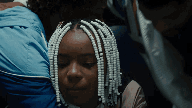 a girl with white beads in her hair looks at the camera