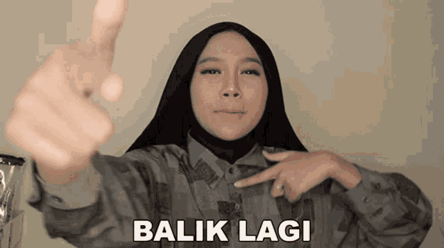 a woman wearing a hijab pointing at the camera with the words balik lagi written on the bottom