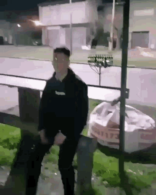 a man in a black sweatshirt with the word supreme on the front is standing in front of a trash can