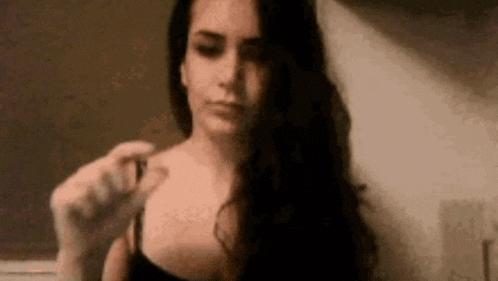 a woman with long hair is holding a small object in her hand and looking at the camera .