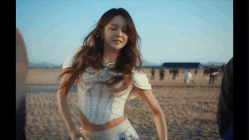 a woman in a white top is dancing on a beach