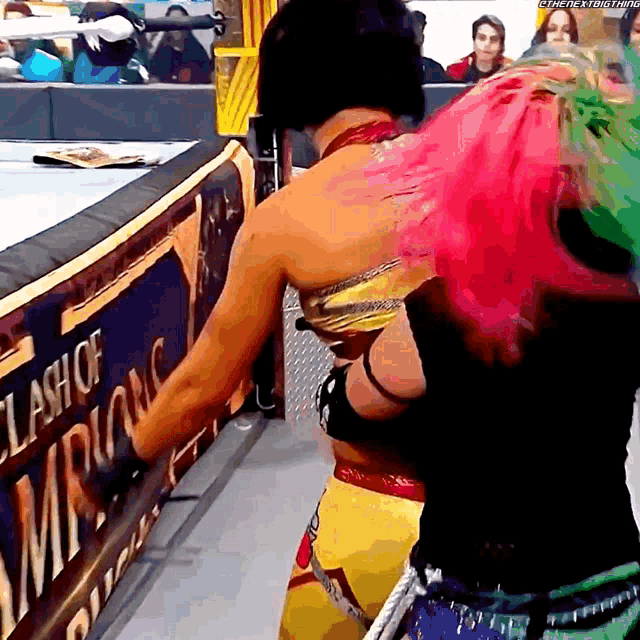 two women wrestling in front of a clash of champions banner