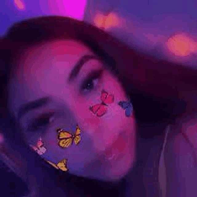 a girl with butterflies on her face is taking a selfie .