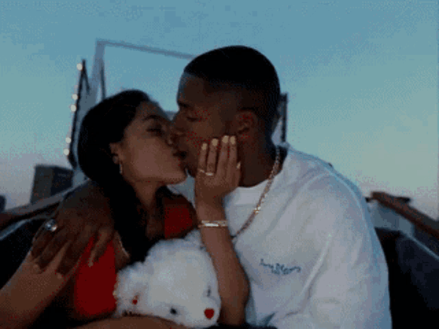 a man and woman are kissing while the man is wearing a white shirt that says supreme