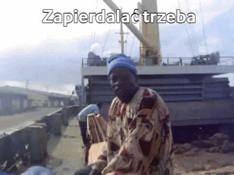 a man wearing a blue hat is sitting in front of a large ship with the words zapierdalac trzeba on the bottom