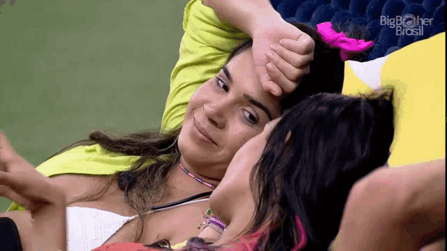 two women laying next to each other with big brother brasil on the bottom