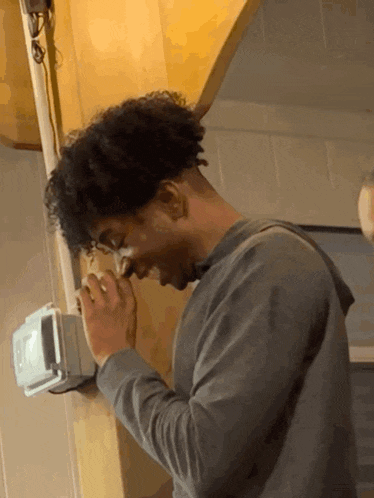 a man with curly hair looks down at something in a room