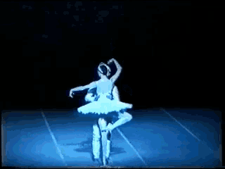 a couple of ballerinas dancing on a stage with a blue light behind them