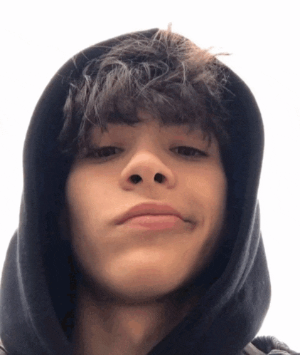 a young man wearing a black hoodie looks at the camera with his eyes closed