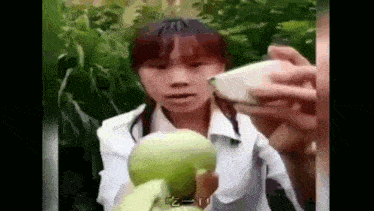 a young girl is holding a green apple in her hands and eating it .