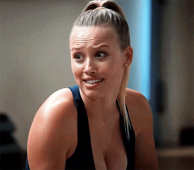 a woman with a ponytail and a plunging neckline is smiling .