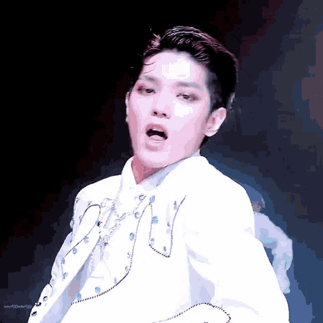 a man in a white suit is making a funny face .