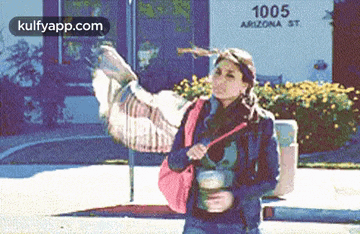 a woman is holding a cup of coffee while a turkey is flying in the background