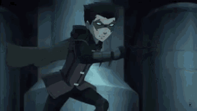 a man in a black suit is standing in a dark room with a gun .