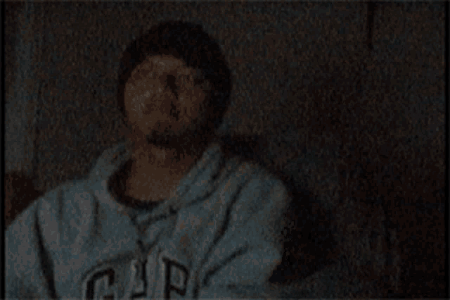 a man wearing a beanie is making a funny face in a dark room .