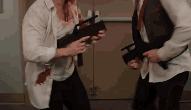 two men are standing next to each other holding guns in front of a door .