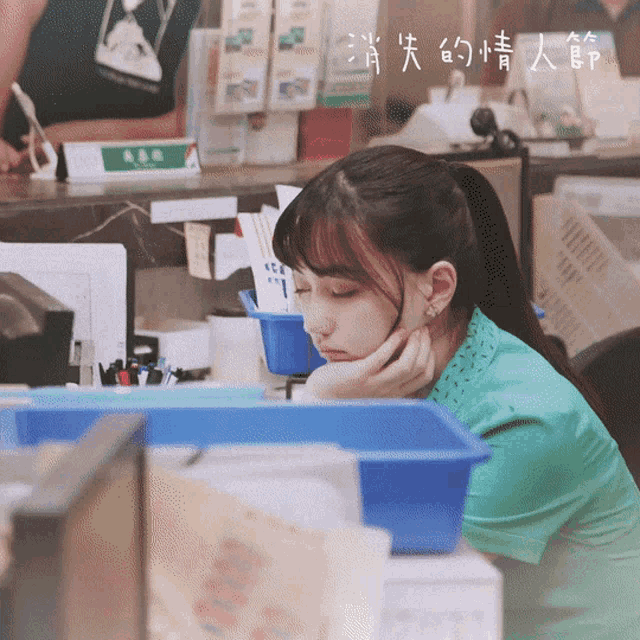a woman in a green shirt sits at a counter with chinese writing on the bottom