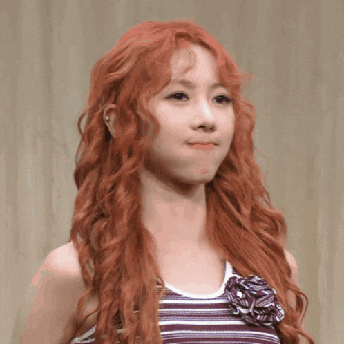 a woman with red hair is wearing a striped tank top with a flower on it