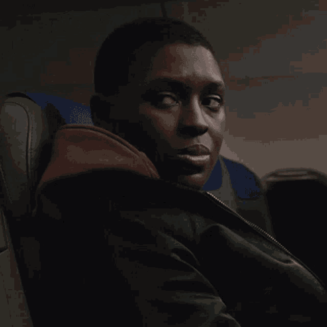 a man in a black jacket is sitting in a chair