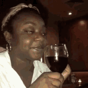 a woman is holding a glass of red wine .
