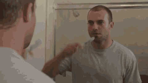 a man brushing his teeth in a bathroom mirror