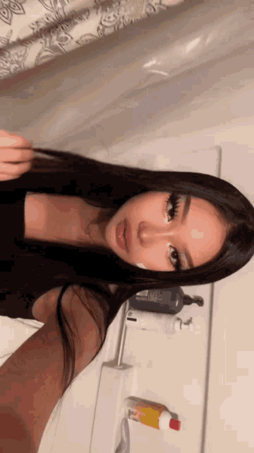 a woman is taking a selfie in a bathroom with a shower curtain behind her .