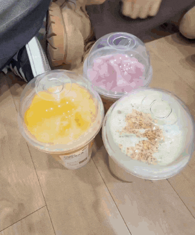 three plastic cups of different flavors are on the floor