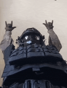 a man wearing a helmet and sunglasses is making a devil horns sign with his hands