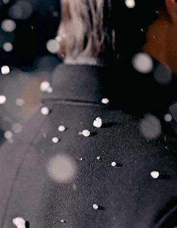 a person is standing in a dark room with petals falling from the sky