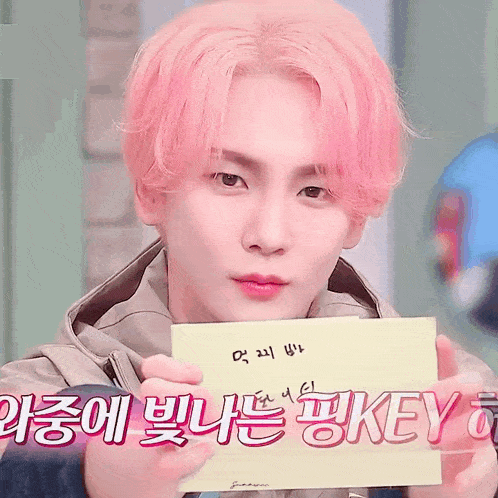 a boy with pink hair is holding a piece of paper that says key on it