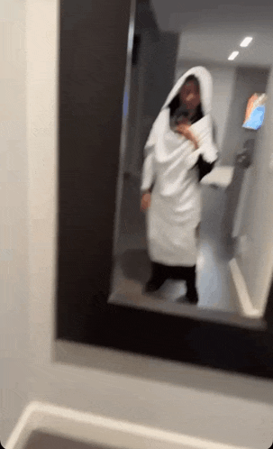 a person in a white robe is taking a selfie in front of a mirror