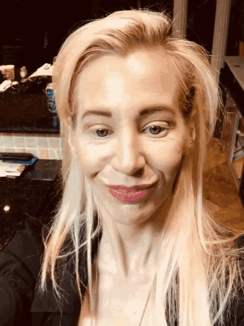 a woman with blonde hair and red lipstick is smiling for the camera