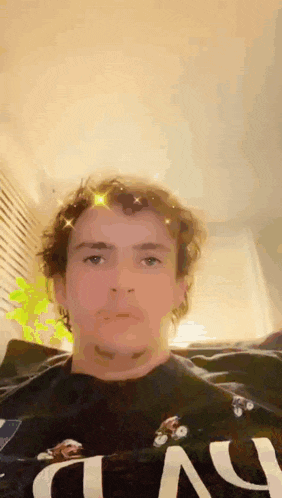 a man with curly hair and a beard is wearing a black shirt with the word n on it .
