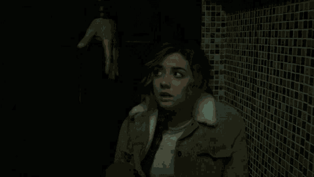 a woman in a brown jacket with a fur collar is standing next to a man in a dark room .