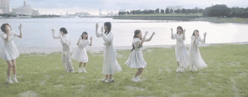a group of girls in white dresses are dancing in a field